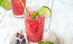 Two glasses of cherry lime mocktail, cherry fizzy drink garnished with lime and mint